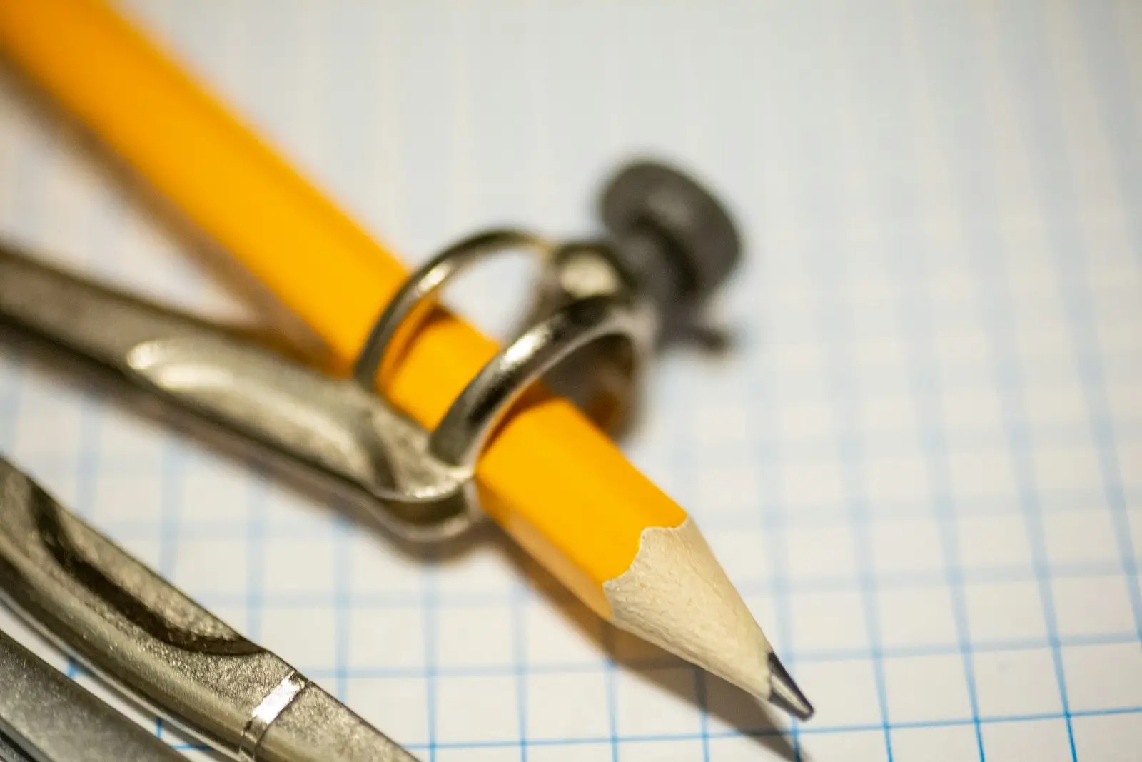A pencil and compass resting on graph paper.
